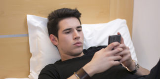 Man holding phone in bed