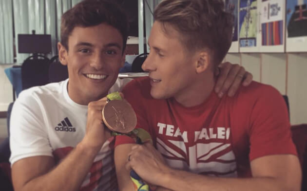 Tom Daley and Dustin Lance Black holding the medal