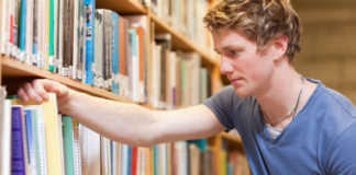 student in the library with books and magazines