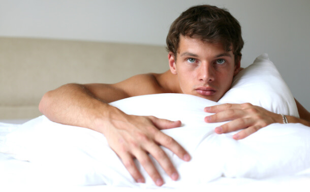 Shirtless man in bed on a pillow